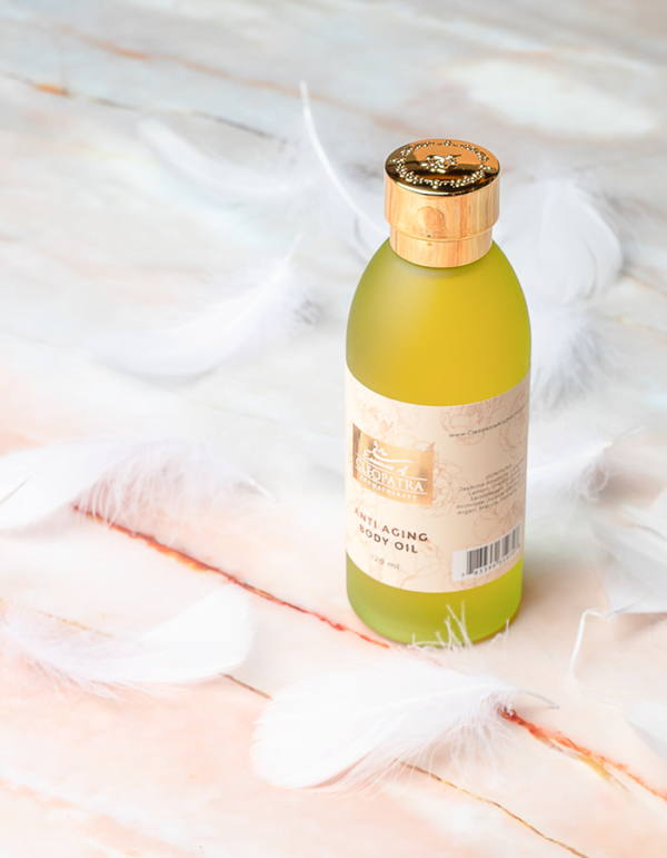 a bottle of ANTI AGING BODY OIL surrounded by white feathers.