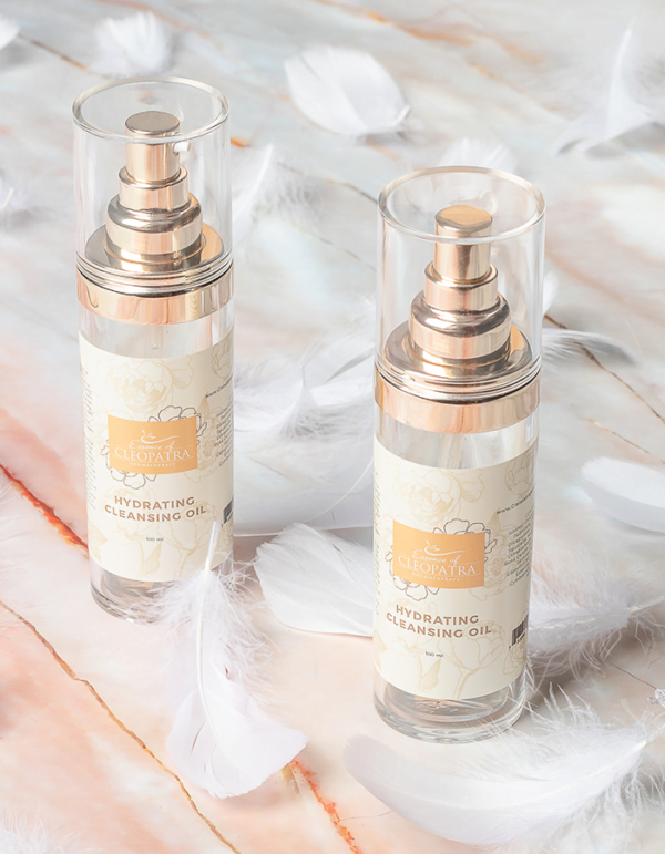 two HYDRATING CLEANSING OIL bottles with white feathers on a marble table.