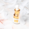 a bottle of YOUTH SERUM ELIXIR with white feathers on a marble table.